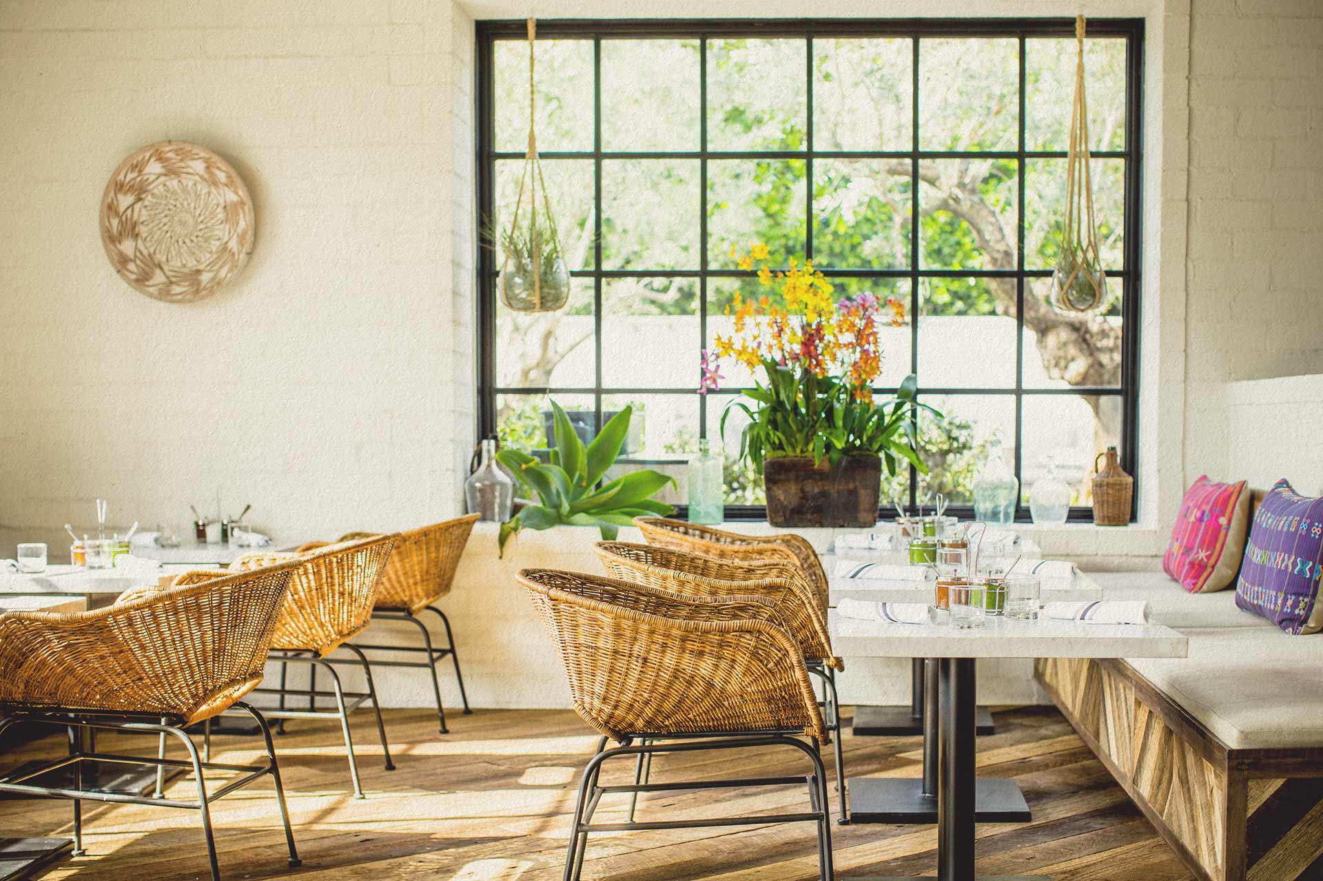 Lounge tables and wicker chairs inside Gracias Madre West Hollywood.