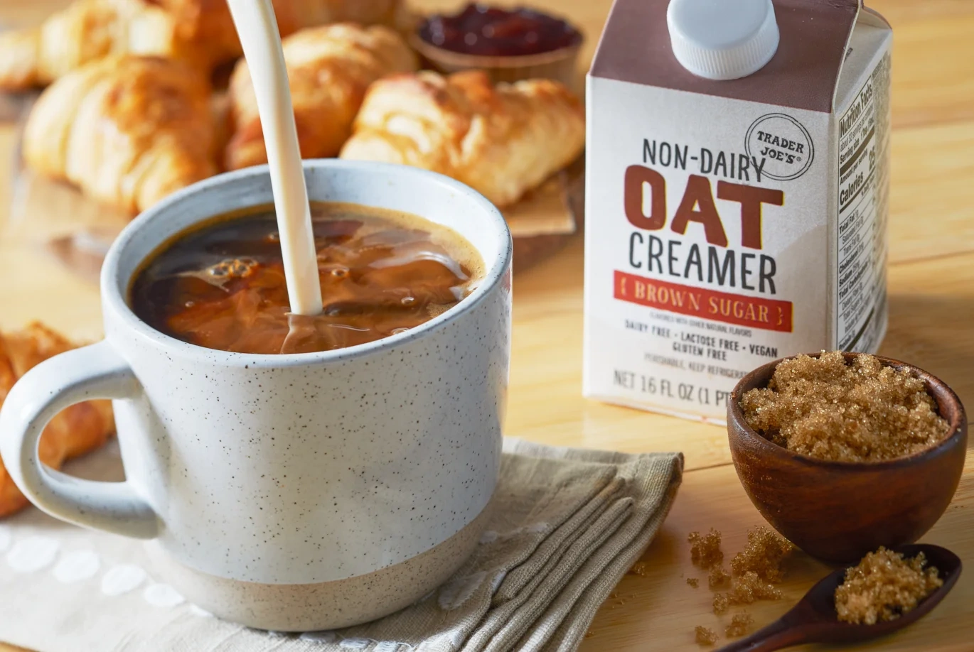 Trader Joe's Brown Sugar Oat Creamer beside iced coffee as creamer is poured into the glass.