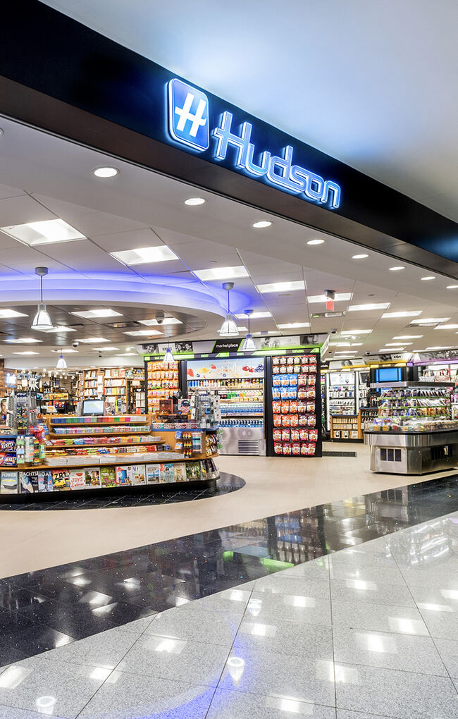 Hudson airport market with shelves, coolers, snacks, magazines, and travel items.