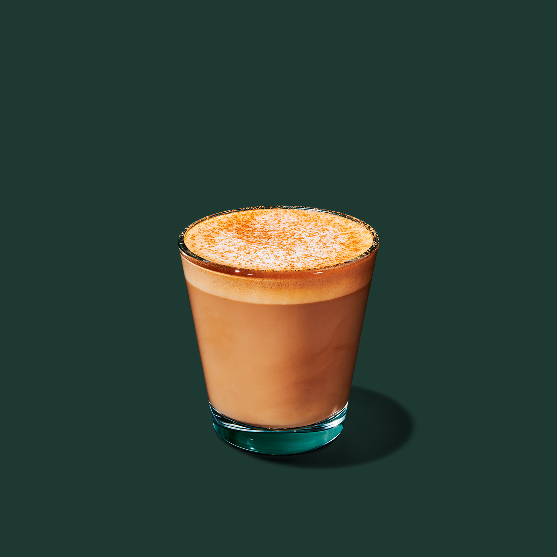 Vegan Starbucks order with a small Brown Sugar Oatmilk Cortado in a glass against a dark green background.
