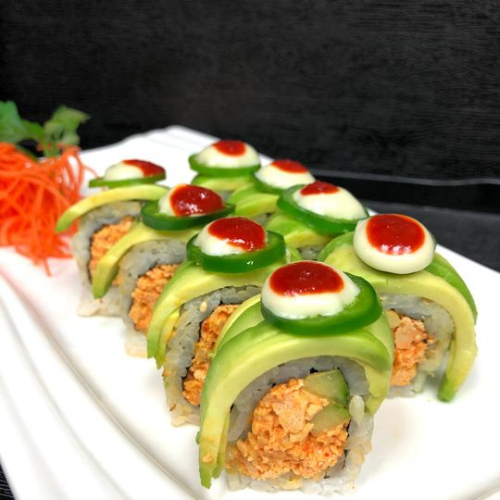 Daikon Vegan Sushi's Caterpillar Roll topped with avocado, jalapeño, and sauce on a white plate.