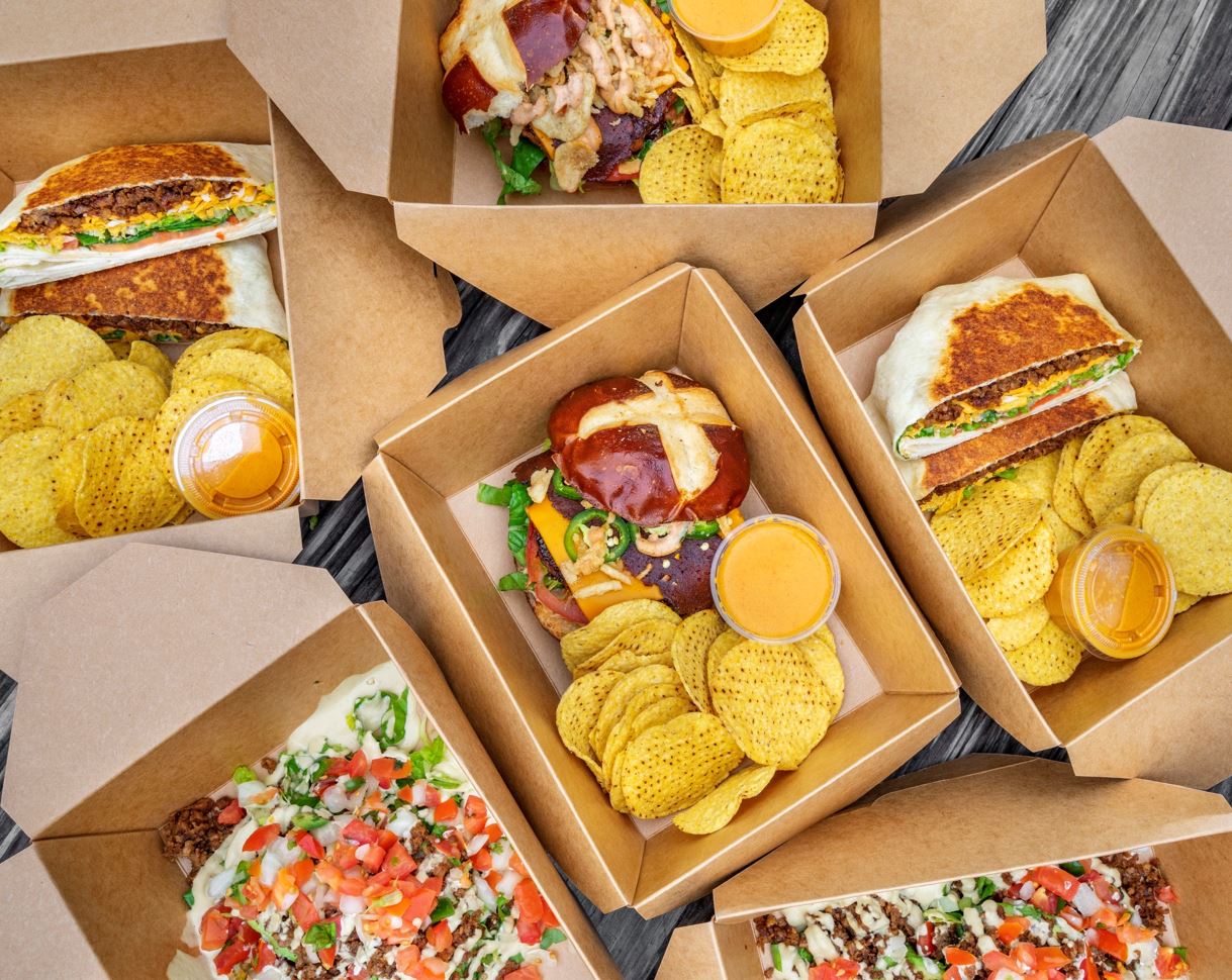 Boxed burgers, folded Crunchwraps, and chips at Vegan Vibrationz.